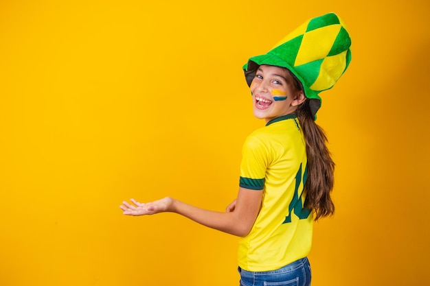 Fã brasileira de costas em fundo amarelo com camisa do brasil
