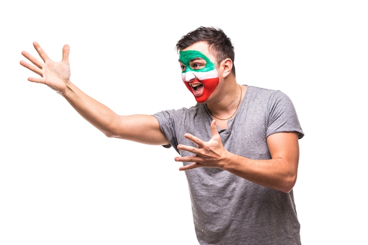 Foto grátis fã de torcedor do homem bonito da equipe nacional do irã pintado com o rosto da bandeira obter a vitória feliz gritando apontado com a mão. emoções dos fãs.