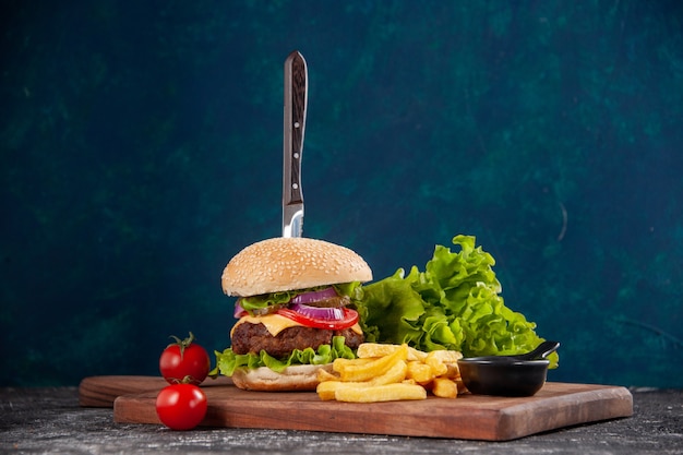 Faca em sanduíche de carne e tomate frita com haste em uma placa de ketchup na superfície azul escura