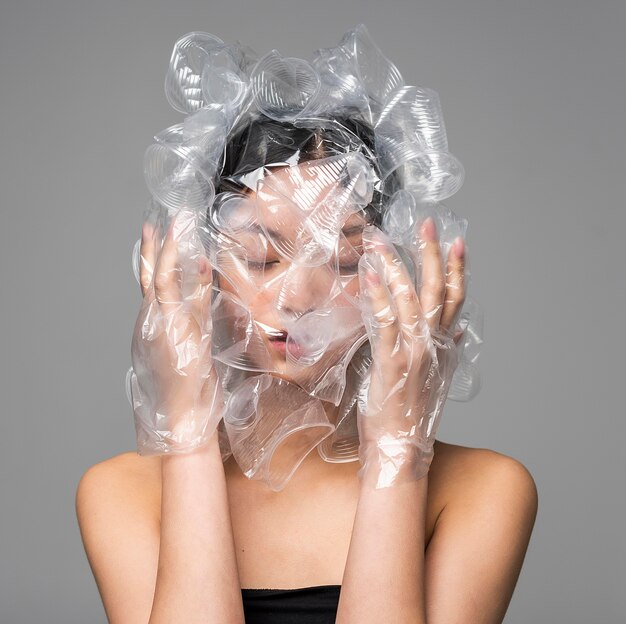 Face frontal da mulher asiática sendo coberta por copos plásticos