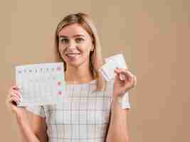 Foto grátis falso mulher sorridente segurando almofadas e calendário do período