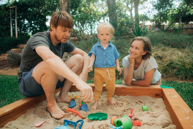 Foto grátis família alegre brincando junta na caixa de areia