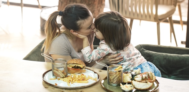 Família amorosa. mãe com filha comendo fast food em um café, família e conceito de nutrição