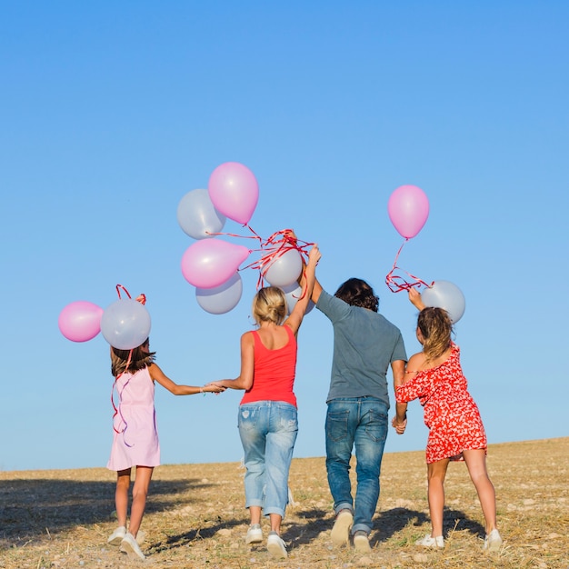 Família andando no campo com balões