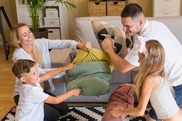 Família brincando com almofadas dentro de casa