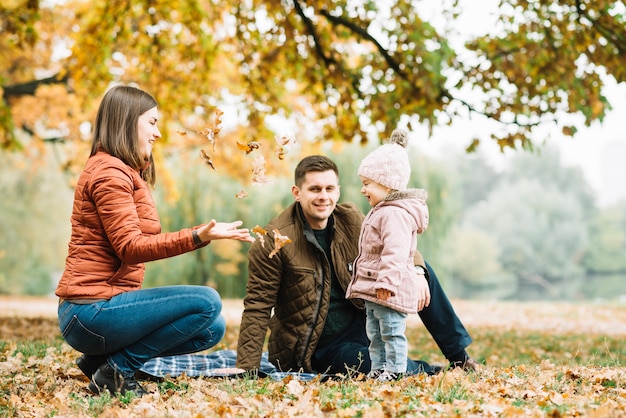 Família brincando com folhas na floresta de outono