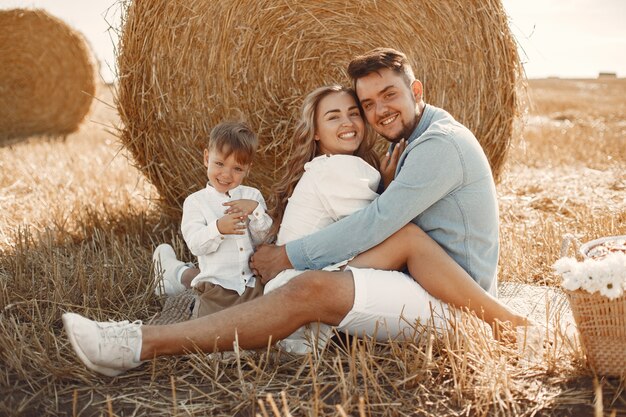 Família brincando com o filho bebê no campo de trigo no pôr do sol. O conceito de férias de verão. Família passando um tempo juntos na natureza.