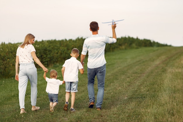 Família caminhando em um campo brincando com um avião de brinquedo