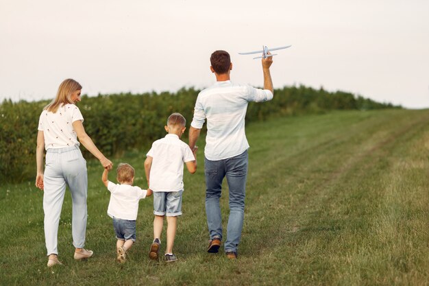 Família caminhando em um campo brincando com um avião de brinquedo