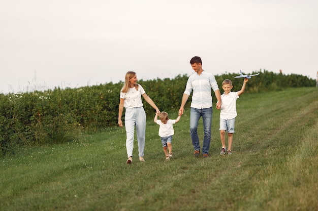 Família caminhando em um campo brincando com um avião de brinquedo