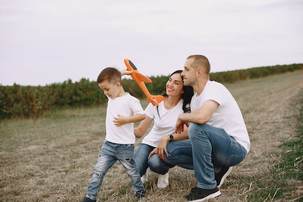 Família caminhando em um campo brincando com um avião de brinquedo