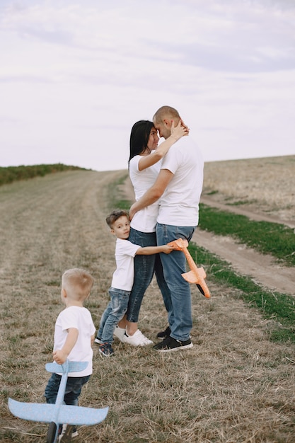 Foto grátis família caminhando em um campo brincando com um avião de brinquedo
