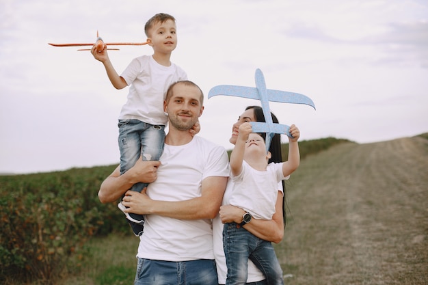 Família caminhando em um campo brincando com um avião de brinquedo