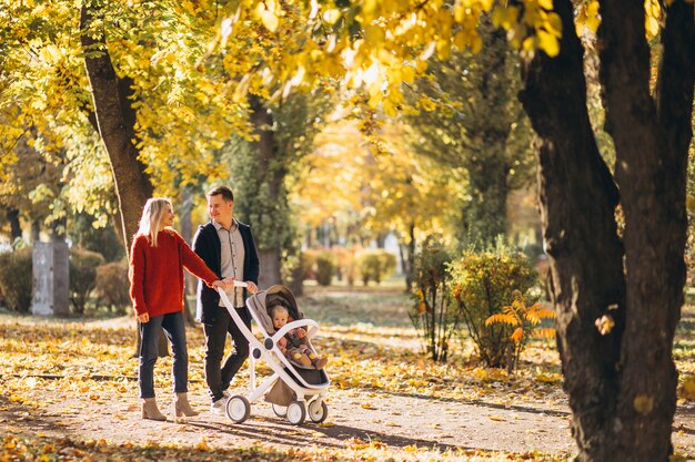 Família com bebê daugher em um carrinho de bebê andando em um parque de outono