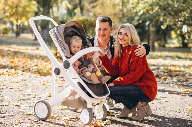 Família com bebê daugher em um carrinho de bebê andando em um parque de outono