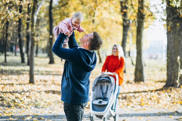 Família com bebê filha caminhando em um parque de outono