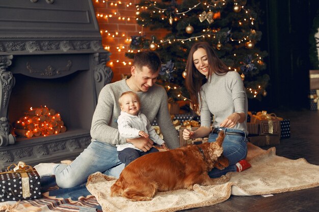 Família com cachorro fofo em casa perto da árvore de natal