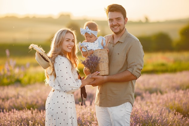 Família com filha no campo de lavanda. mulher bonita e bebê fofo brincando no campo do prado. férias em família num dia de verão.