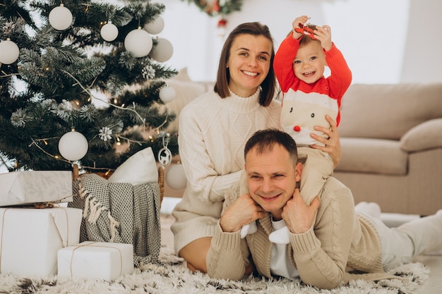 Família com filho pequeno no Natal perto da árvore de natal em casa