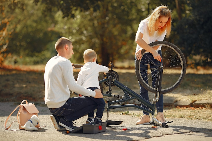 Foto grátis família com filho repare a bicicleta em um parque