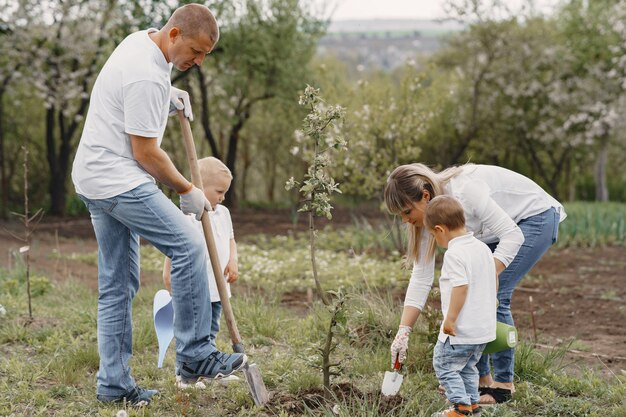 Família com filhos pequenos estão plantando uma árvore em um quintal