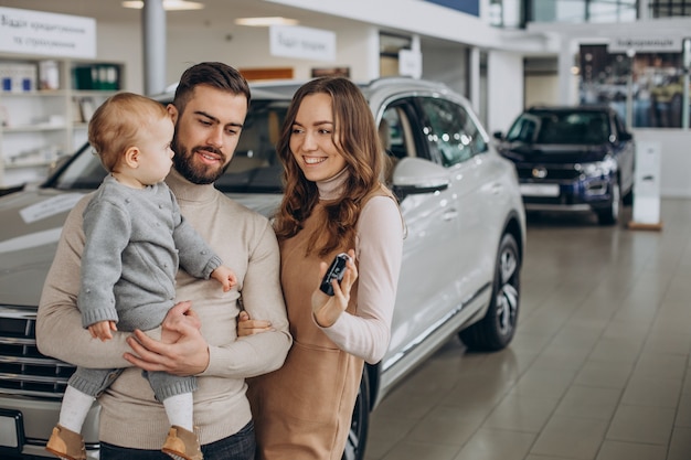 Foto grátis família com garota bbay escolhendo um carro em um salão de carros
