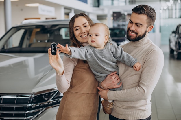 Família com garota bbay escolhendo um carro em um salão de carros