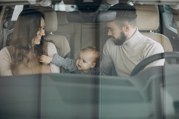 Foto grátis família com garota bbay escolhendo um carro em um salão de carros