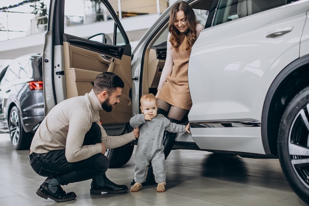 Família com uma linda filha escolhendo um carro em um showroom de carros