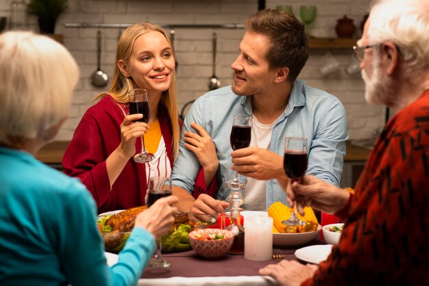 Família conversando e segurando copos de vinho vista frontal