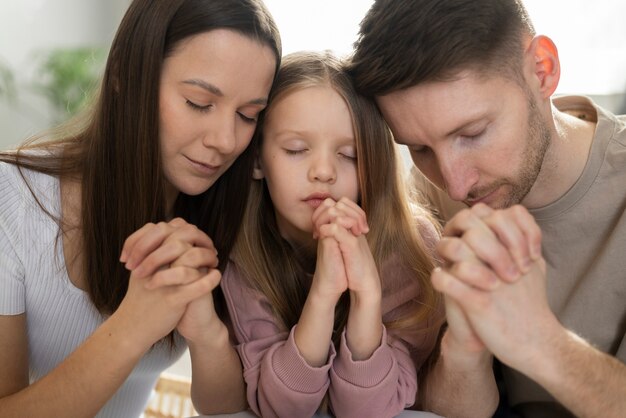 Família cristã de tiro médio rezando juntos