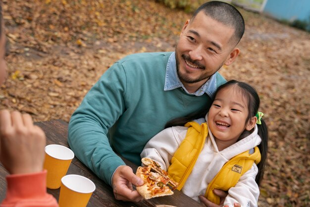 Família de alto ângulo comendo pizza ao ar livre