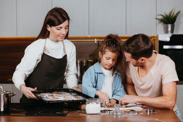 Família de pai e mãe com filha cozinhando juntos em casa