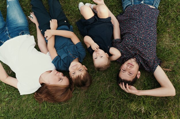 Família de retrato com crianças deitado na grama