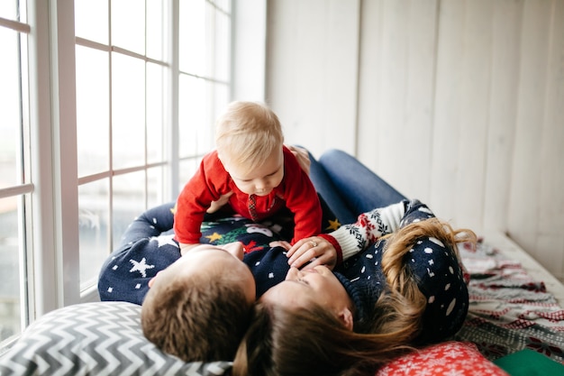 Família de sorriso feliz no estúdio no fundo da árvore de Natal com presente