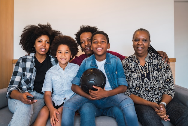 Família de várias gerações, assistindo a partida de futebol em casa.