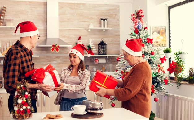 Família de várias gerações comemorando o Natal com caixas de presente