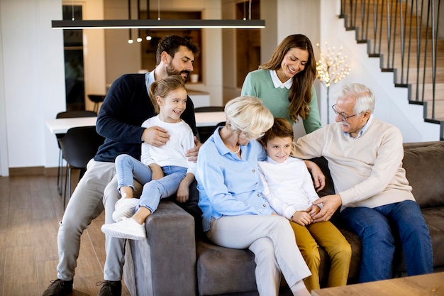 Família de várias gerações sentados juntos no sofá em uma casa moderna e assistindo tv