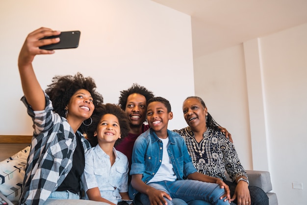 Família de várias gerações, tendo selfie com telefone em casa.