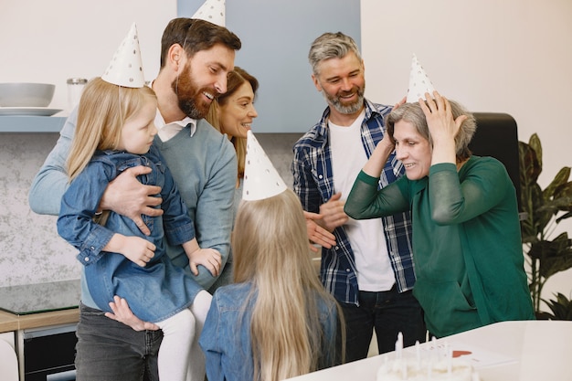 Família e duas filhas comemoram aniversário da avó. pessoas usam chapéu de festa