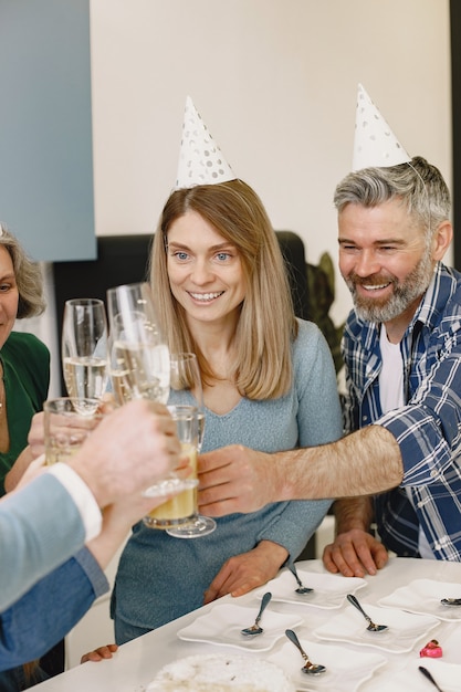 Família e duas filhas comemoram aniversário de avós. pessoas estão batendo em seus copos com champanhe