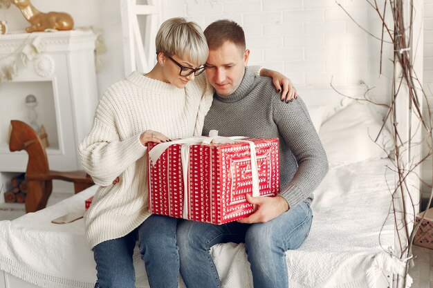 Família em casa. Casal perto de decorações de Natal. Mulher com um suéter cinza.