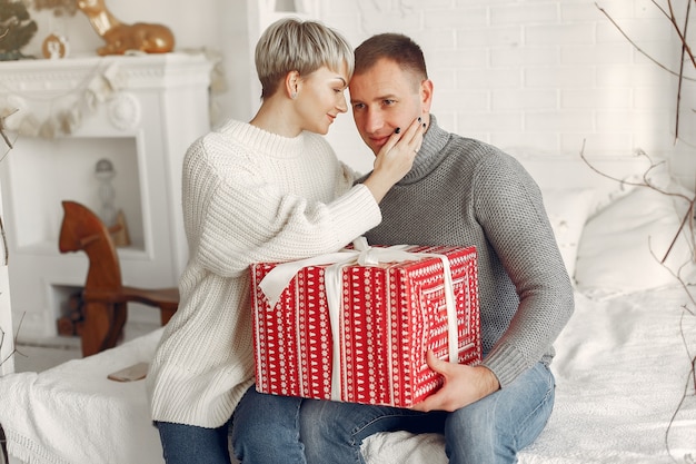 Família em casa. Casal perto de decorações de Natal. Mulher com um suéter cinza.