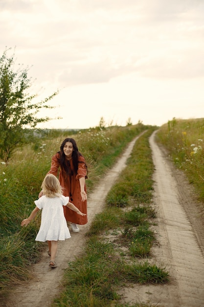 Família em um campo de verão. mãe em um vestido marrom. menina bonitinha.