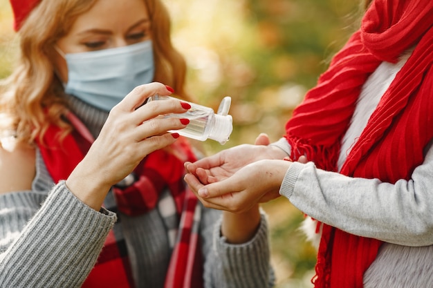 Família em um parque de outono. Tema Coronavirus. Mãe com filha. As pessoas usam anti-séptico.