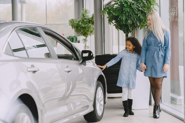 Família em um salão de automóveis. Mulher comprando o carro. Menina africana com mther.