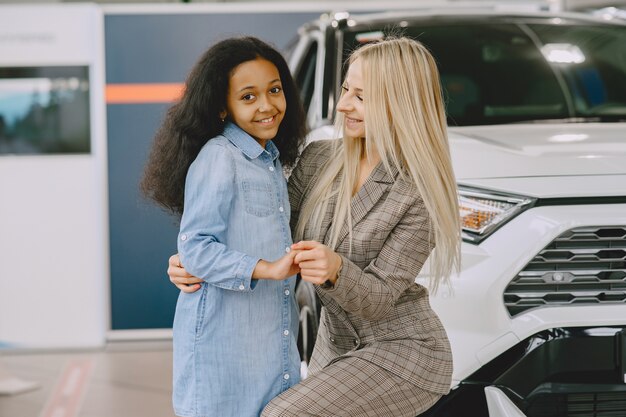 Família em um salão de automóveis. Mulher comprando o carro. Menina africana com mther.