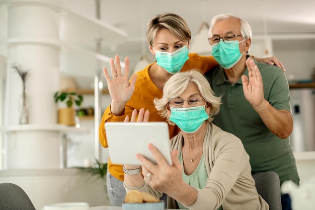 Família feliz acenando enquanto faz videochamada pelo touchpad em casa durante a pandemia COVID19