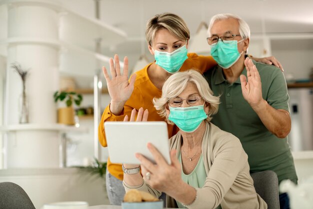 Família feliz acenando enquanto faz videochamada pelo touchpad em casa durante a pandemia COVID19