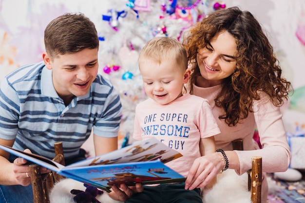 Família feliz coloca diante de uma árvore de Natal em sala rosa